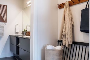 A modern bathroom with a mirror, sink, and towel rack. - Cabot Peak Retreat - This professionally curated, design-forward condo is your perfect basecamp, located just minutes from both downtown and the world-class slopes of Revelstoke Mountain Resort. (Revelstoke)