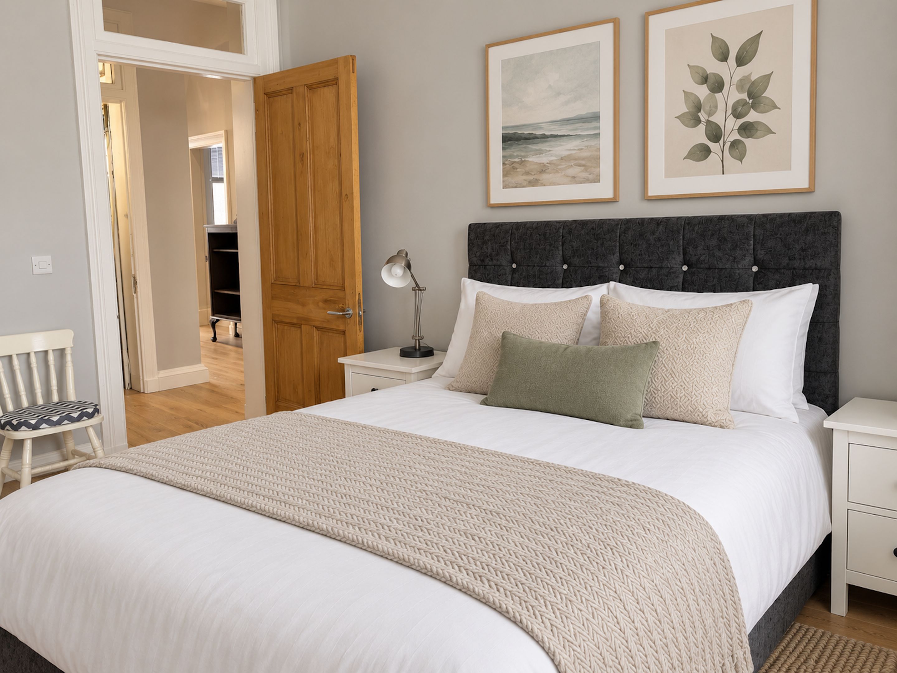 A bedroom with a bed, nightstands, a chair, and artwork on the wall.