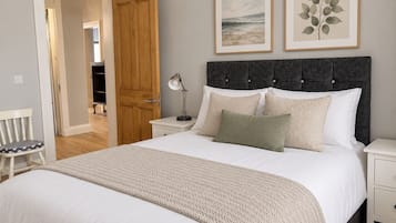 A bedroom with a bed, nightstands, a chair, and artwork on the wall.