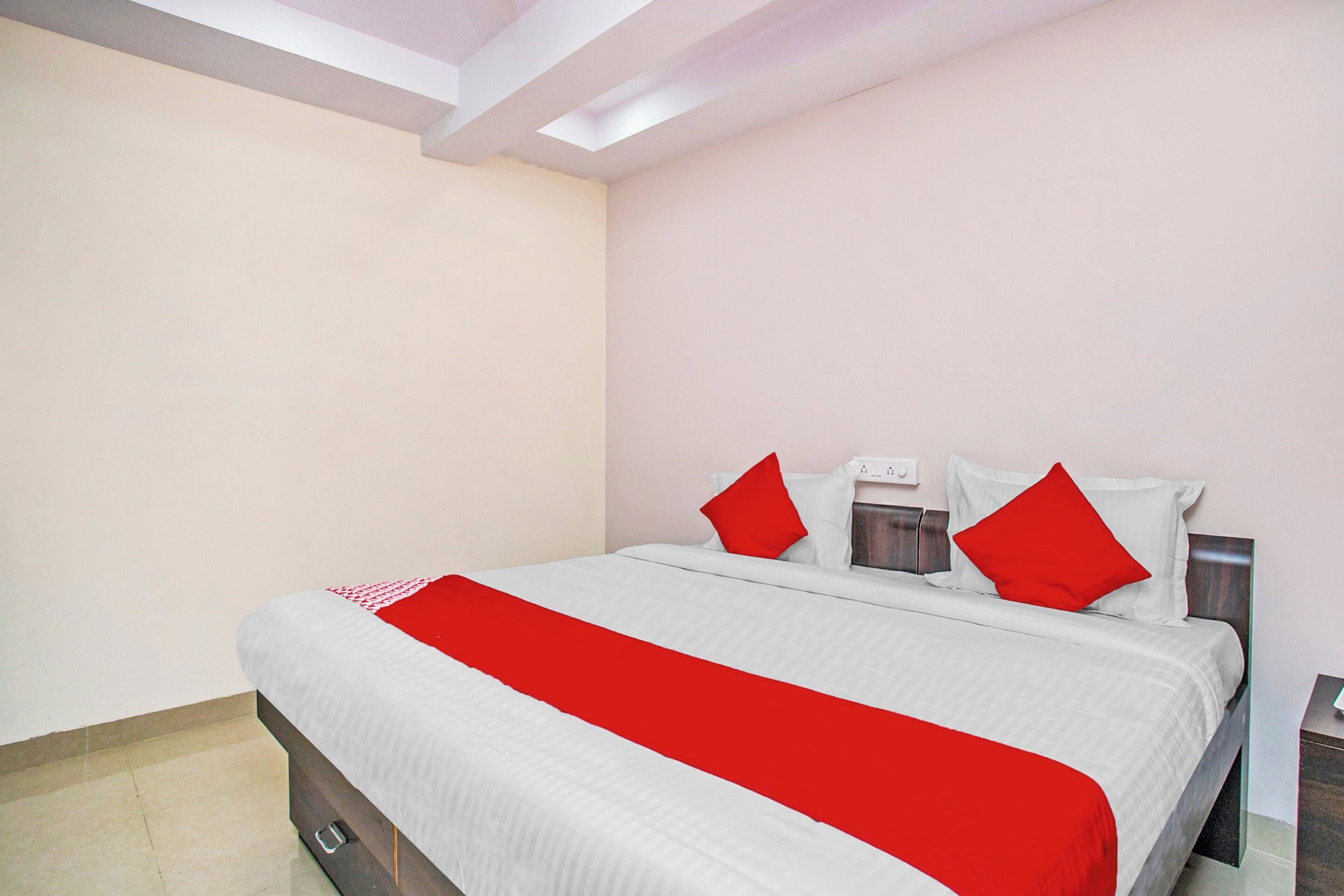 A hotel room with a bed, a nightstand, and a wall socket.
