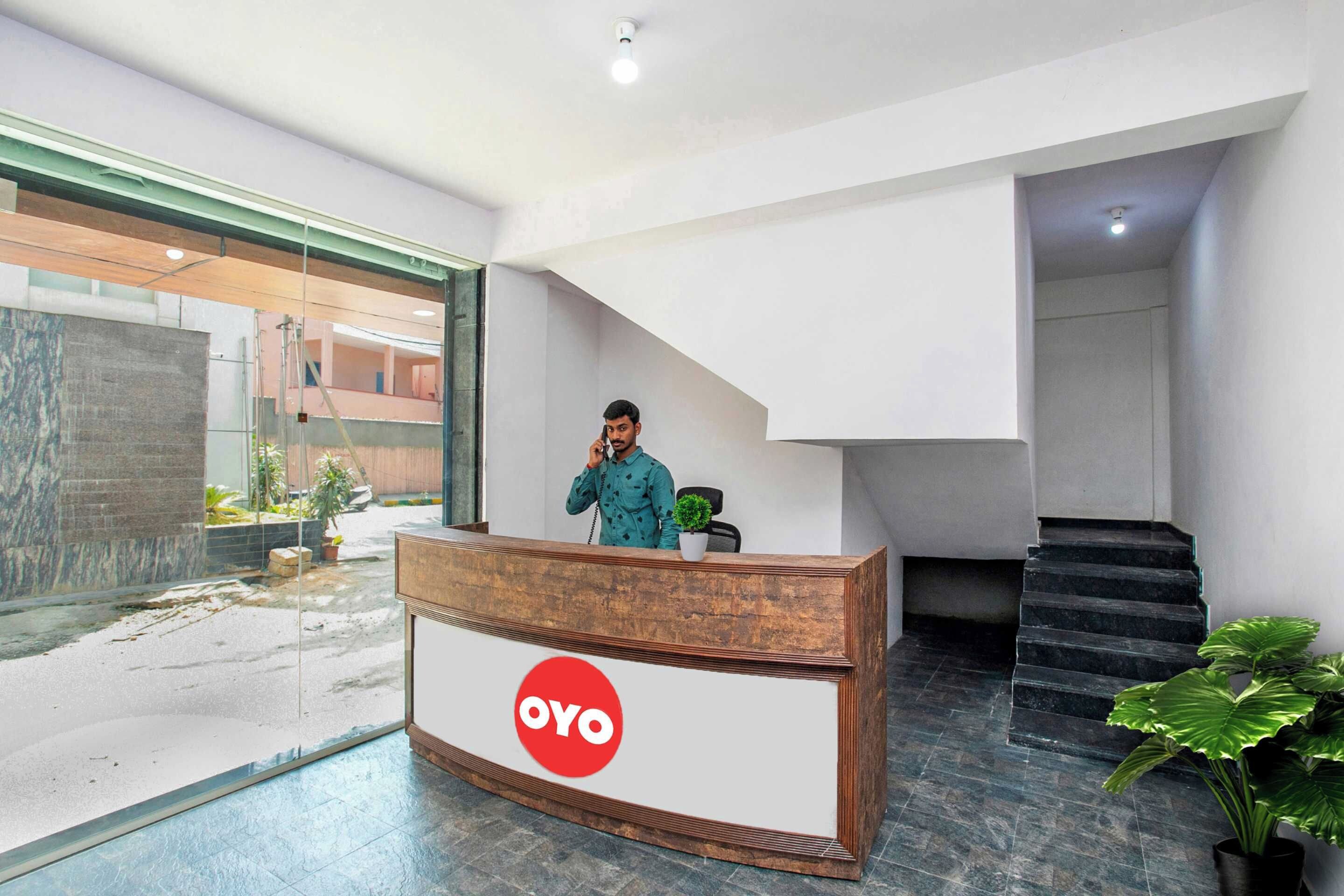 A reception desk with a logo, a staircase, and a view of the outside.