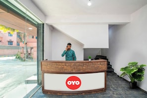 Una recepción con un logotipo, un hombre de pie detrás y una escalera que sube a un nivel superior.