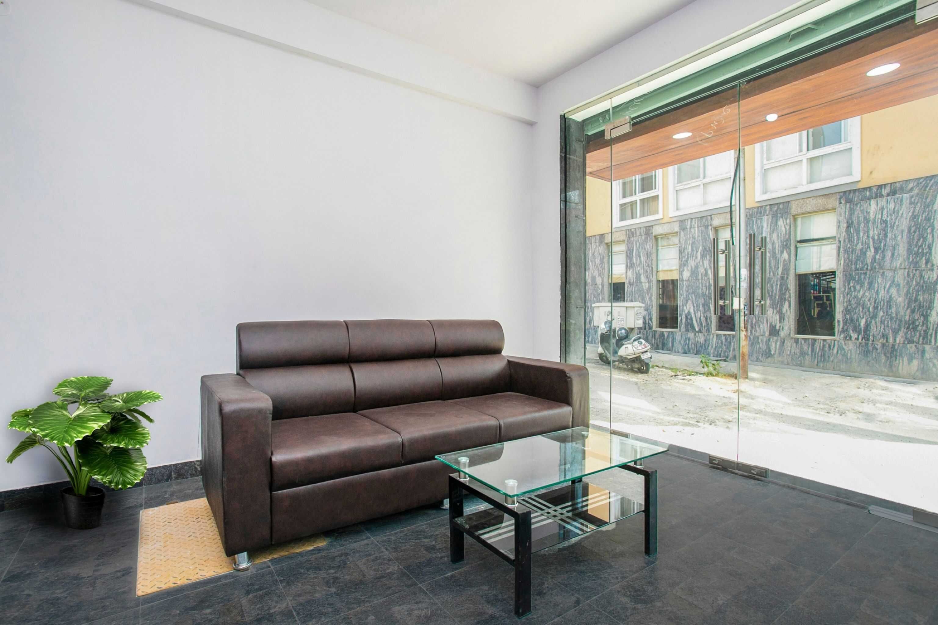 A modern interior with a leather sofa, a glass coffee table, and a potted plant.