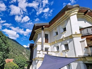 Ein Gebäude mit weißer Fassade, zahlreichen Fenstern und einem Balkon.