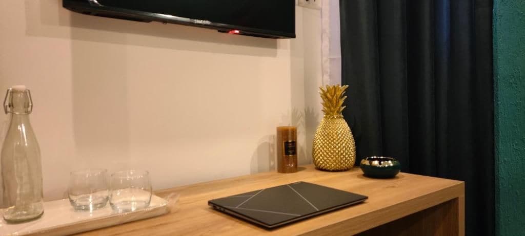 Une table en bois avec une tablette, un ananas, une bougie et une bouteille.