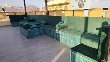 Una terraza en la azotea con un área de estar acolchada de color verde y suelo de baldosas.