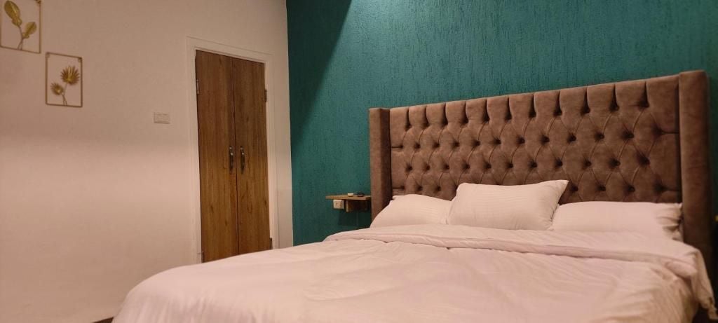 Un dormitorio con un cabecero acolchado, una puerta de madera y una pared de acento color turquesa.