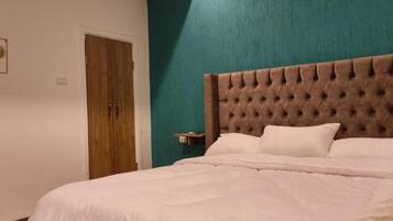 Un dormitorio con un cabecero acolchado, una puerta de madera y una pared de acento color turquesa.