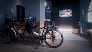 A room with a bicycle, a clock, and a television on the wall. - BLUE STONE H (Madaba)