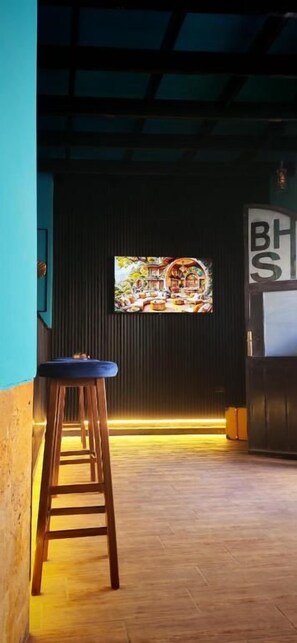 A bar area with a stool, a television screen, and a sign with 'BHS' on it. - BLUE STONE H (Madaba)