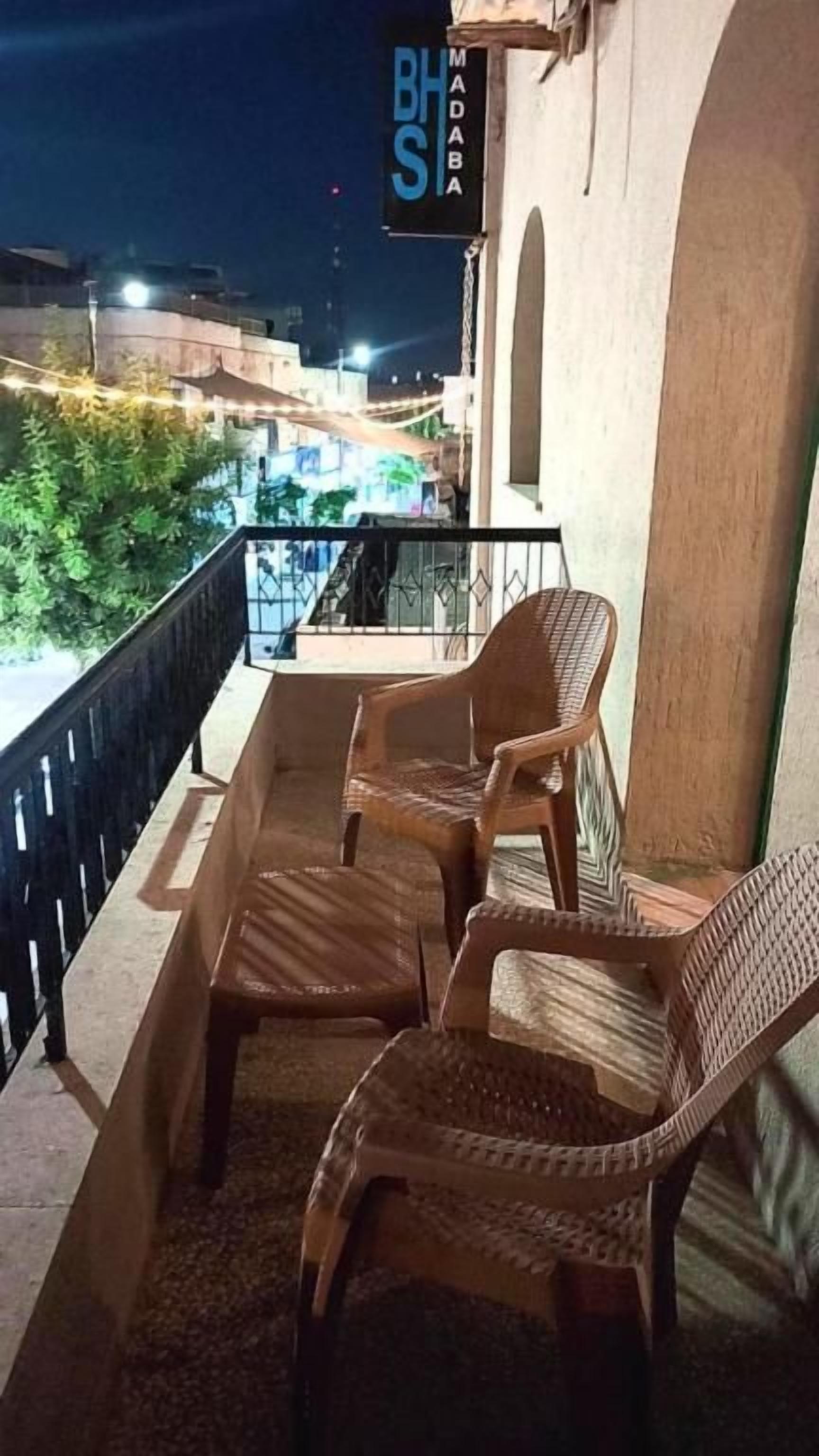 Un balcon avec des fauteuils en osier et une enseigne au-dessus.