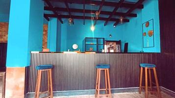 A bar area with a blue wall, wooden stools, and a counter.