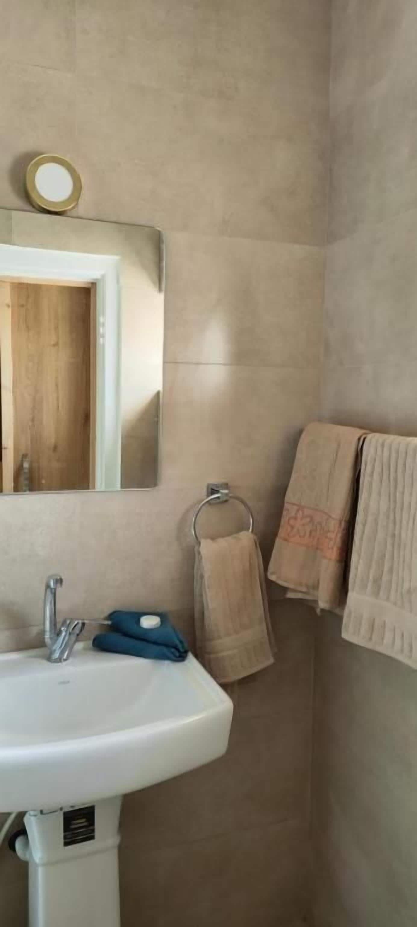 Un baño con lavamanos, espejo y toallas.
