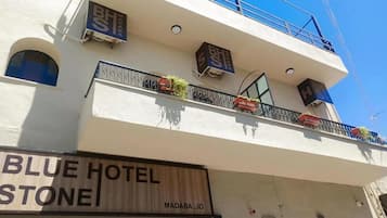 Un hotel con un letrero que dice 'BLUE HOTEL STONE' y balcones con plantas.