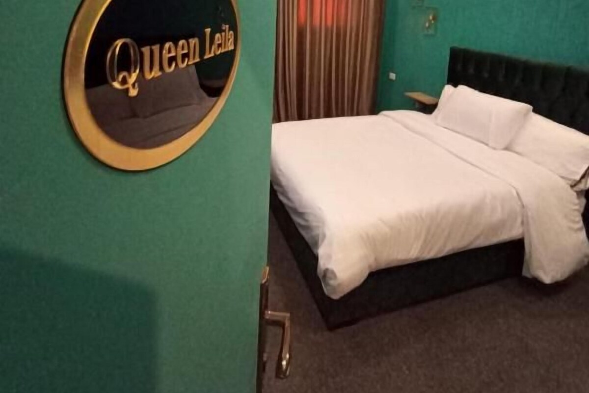 A hotel room with a bed, a circular sign on the wall, and a curtain.