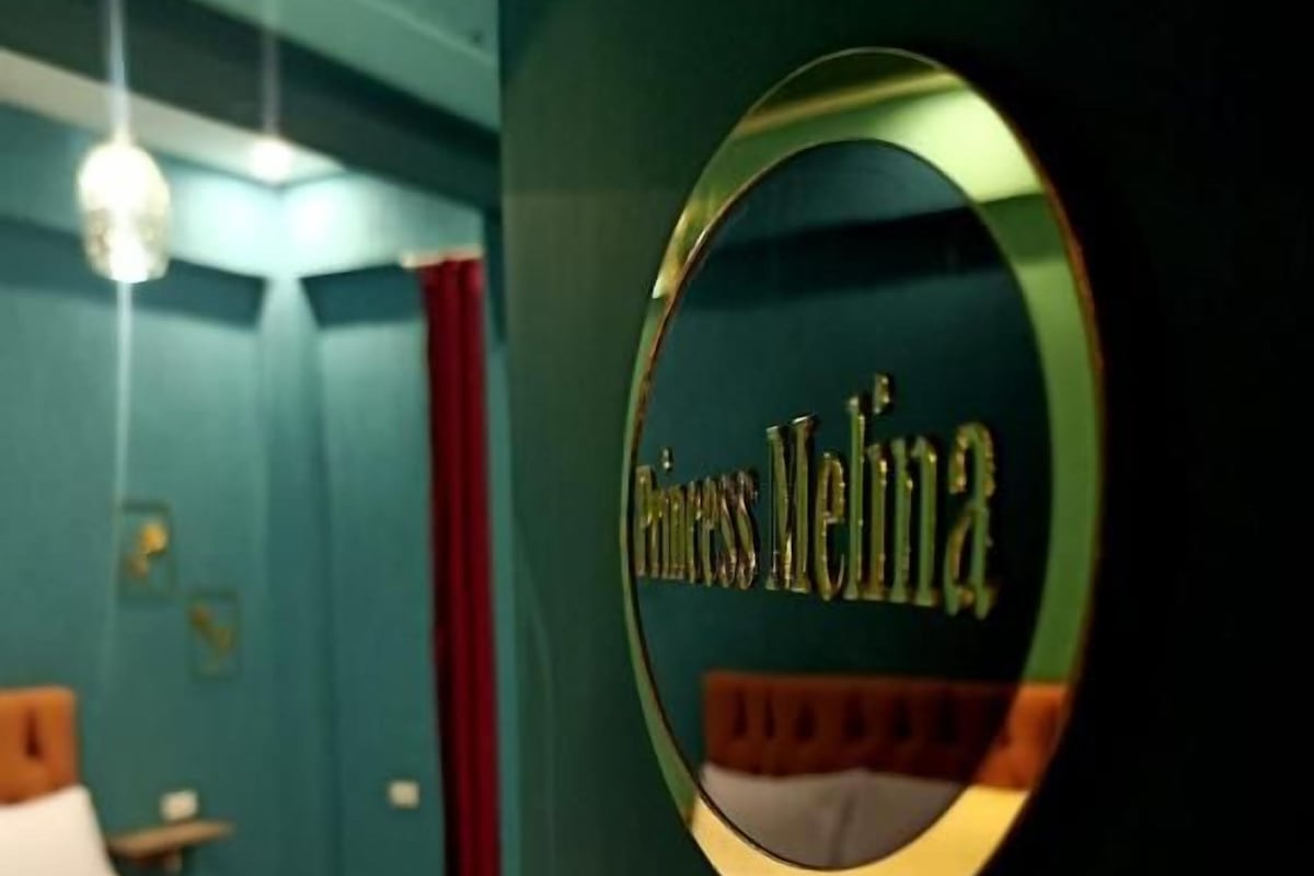 A circular sign with the text 'Princess Meliha' in a room with a bed and a nightstand.