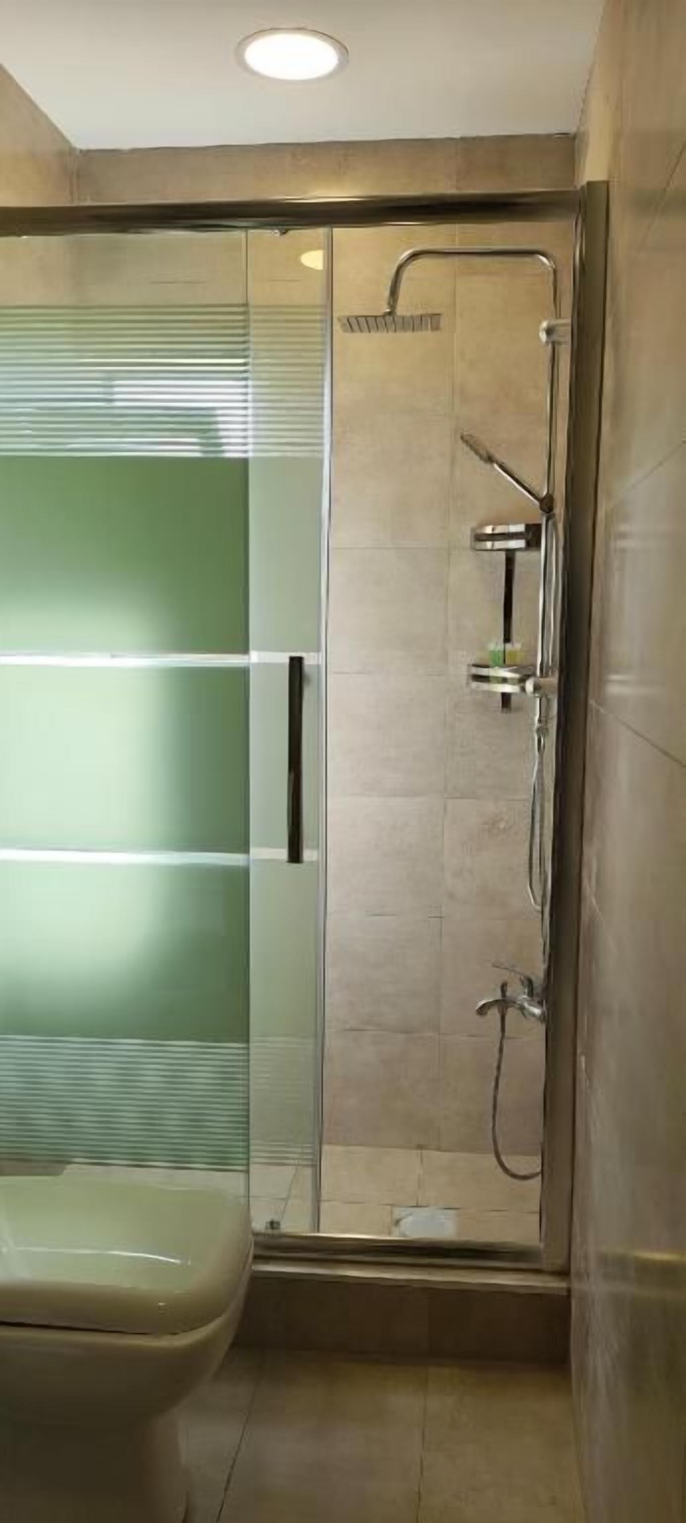 A bathroom with a glass shower enclosure, a toilet, and a sink.
