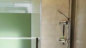 A bathroom with a glass shower enclosure, a toilet, and a sink.