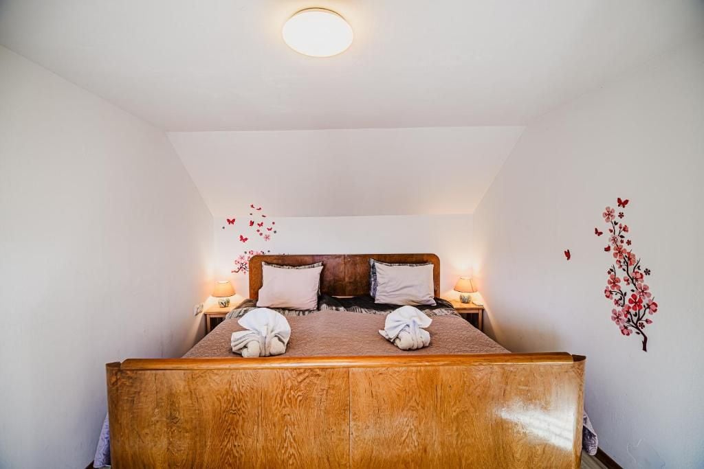 Een enkel bed met een houten hoofdbord, twee kussens en twee bedlampjes.