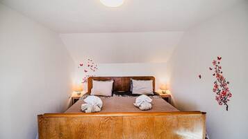 Een enkel bed met een houten hoofdbord, twee kussens en twee bedlampjes.