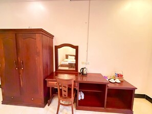 Una habitació amb escriptori de fusta, una cadira, un armari i un mirall.
