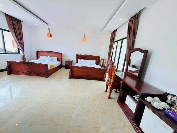 A hotel room with two wooden beds, a large mirror, and a dining area with a table set for tea. - ORA Boutique (Siem Reap)