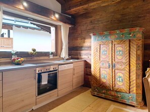 A kitchen with wooden cabinets, a built-in oven, and a decorative cabinet with intricate designs. - Wonderful  villa for 5 people with WIFI, TV and balcony (Kirchberg In Tirol)