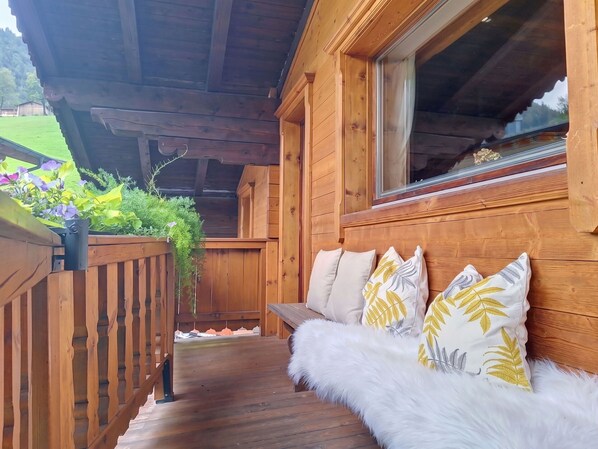 A wooden deck with a bench and cushions, surrounded by greenery and a wooden fence. - Stunning  villa for 5 people with WIFI, TV and balcony (Kirchberg In Tirol)