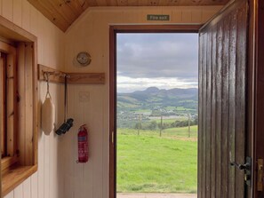 A wooden interior with a fire exit sign, a wall-mounted clock, binoculars, and a fire extinguisher. - Wonderful private villa for 4 guests with WIFI, TV and panoramic view (Inverness)