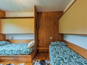 A compact room with two bunk beds, a wooden wardrobe, and a small rug on the floor. - Lovely apartment for 6 people with WIFI, TV and patio (Pinzolo)