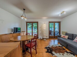 Ein stilvoller Wohnraum mit Essbereich, einer Couch und einem Fernseher.