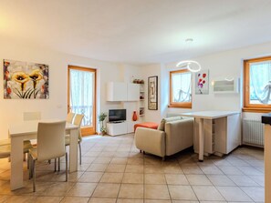 Ein modernes Wohnzimmer mit Essbereich, einer Couch, einem Fernseher und Kunstwerken an den Wänden.