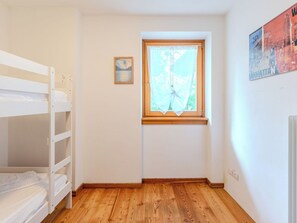 Ein kleines Zimmer mit einem Etagenbett, einem Fenster mit Blick und einem gerahmten Bild an der Wand.