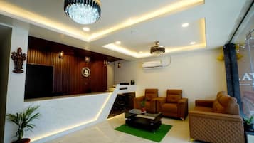 A modern hotel lobby with a reception desk, seating area, and decorative lighting.