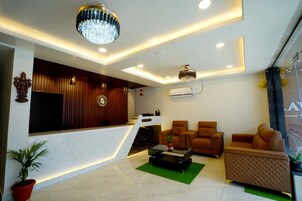 Un moderno vestíbulo de hotel con mostrador de recepción, zona de estar e iluminación decorativa.