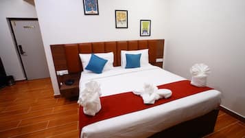 A hotel room with a large bed, a wooden headboard, a red throw blanket, and two pillows.