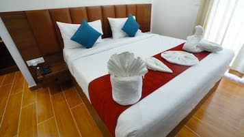 A hotel room with a large bed, a wooden headboard, and a red accent pillow.