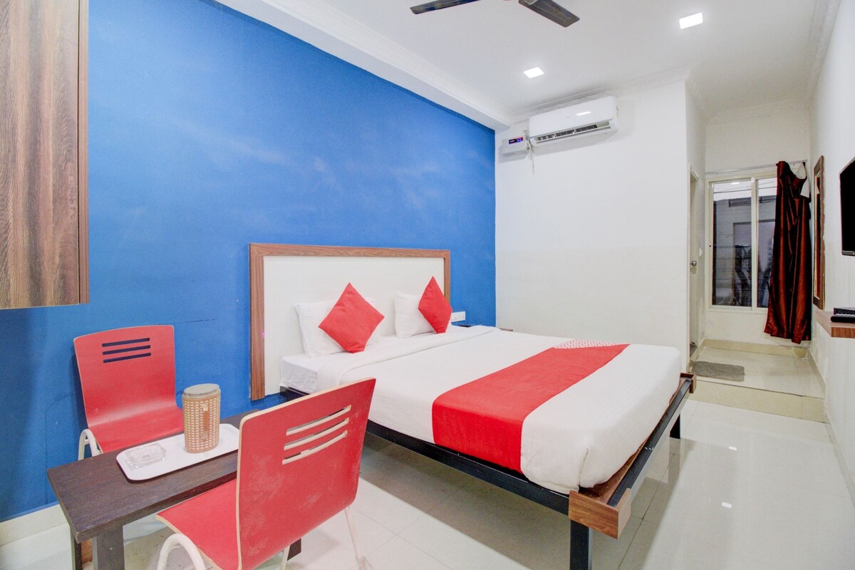 Une chambre d’hôtel avec un lit, un bureau, une chaise et une fenêtre.