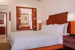 Ein Hotelzimmer mit einem großen Bett, einem hölzernen Kopfteil, einem Nachttisch mit einer Lampe und einem Spiegel.