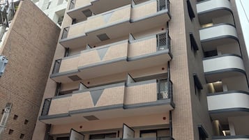 Un edificio de varios pisos con una planta baja comercial, que muestra un letrero de un negocio y una entrada visible.