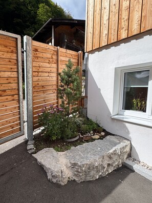 A wooden fence with a small garden area, including a tree and various plants. - Doktorberg Vacation Rental 20.5 (Berchtesgaden)