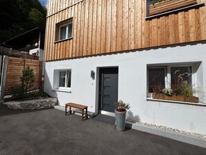 A modern two-story building with a wooden facade, a bench, and potted plants. - Doktorberg Vacation Rental 20.5 (Berchtesgaden)