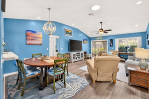 A living room with a TV, a ceiling fan, and a dining area with a table and chairs. - Golfer's Lounge - 3/2 w/ 4-Seat Golf Cart in The Villages - De Le Vista (De La Vista, The Villages)