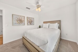 Ein Schlafzimmer mit einem Bett, einem Deckenventilator und zwei an der Wand befestigten Bildern.