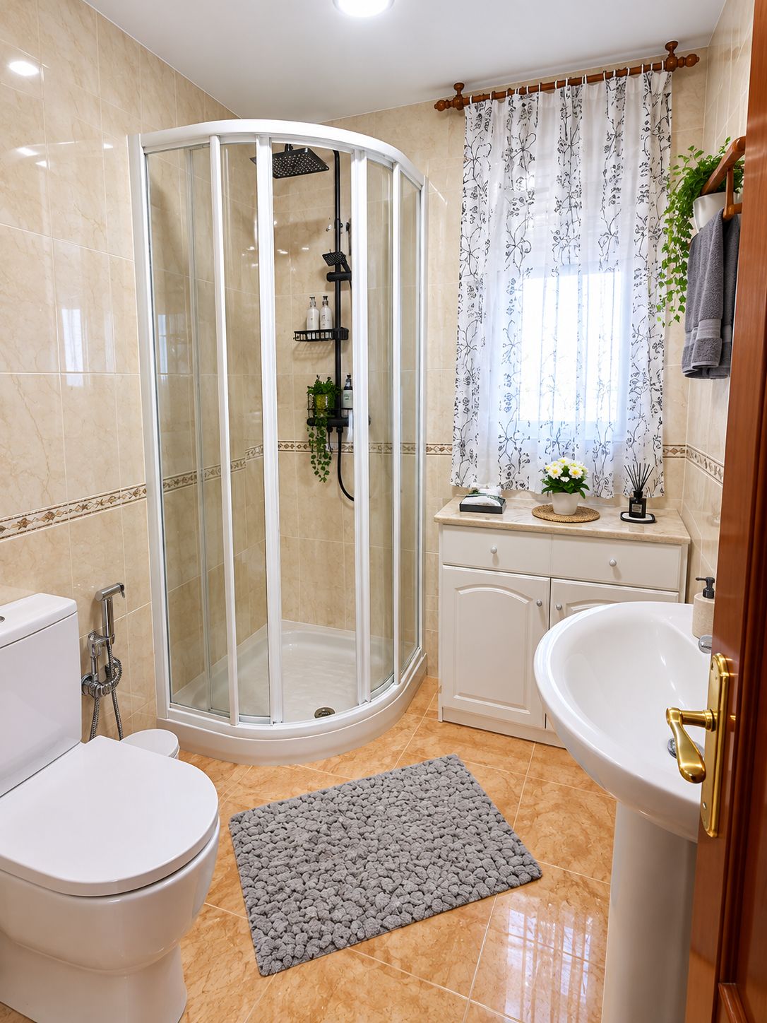 Un baño con ducha envuelta en vidrio, un inodoro, un lavamanos y una cortina de ducha con estampado floral.