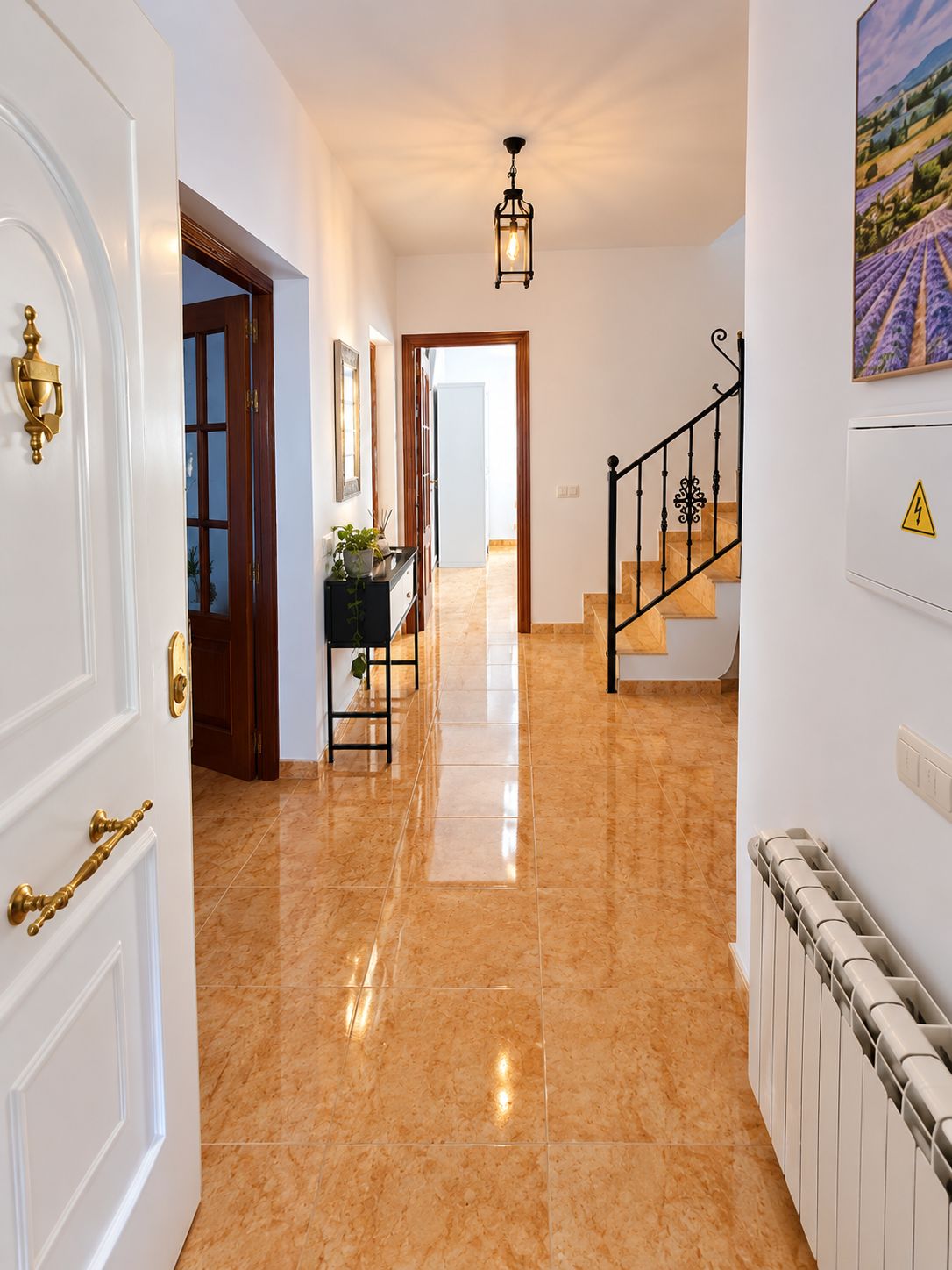 Un pasillo con piso de baldosas, una escalera y una puerta con picaporte de latón.