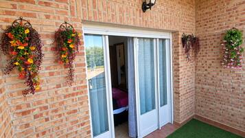 Fachada de ladrillo con puerta corredera de vidrio que da a una habitación.