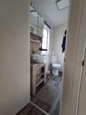 Ein kleines Badezimmer mit Waschbecken, Spiegel und Toilette.