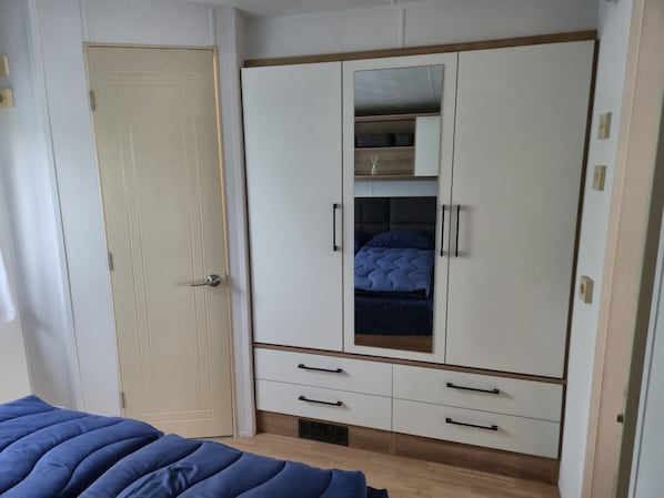 Ein Schlafzimmer mit einem Bett, einem Kleiderschrank mit Spiegel und einer Kommode.