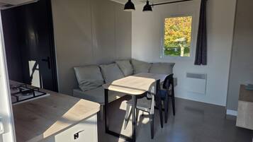 Une cuisine compacte avec un coin repas, une cuisinière intégrée et une fenêtre avec des rideaux.